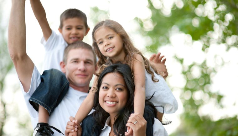 A family with a man, woman, boy, and a girl all outside in white teeshirts.