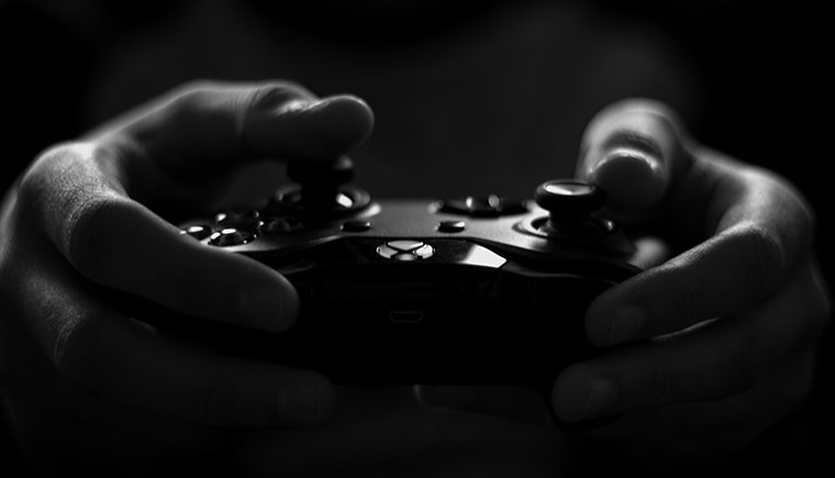 Black and white image of two hands holding a video game controler