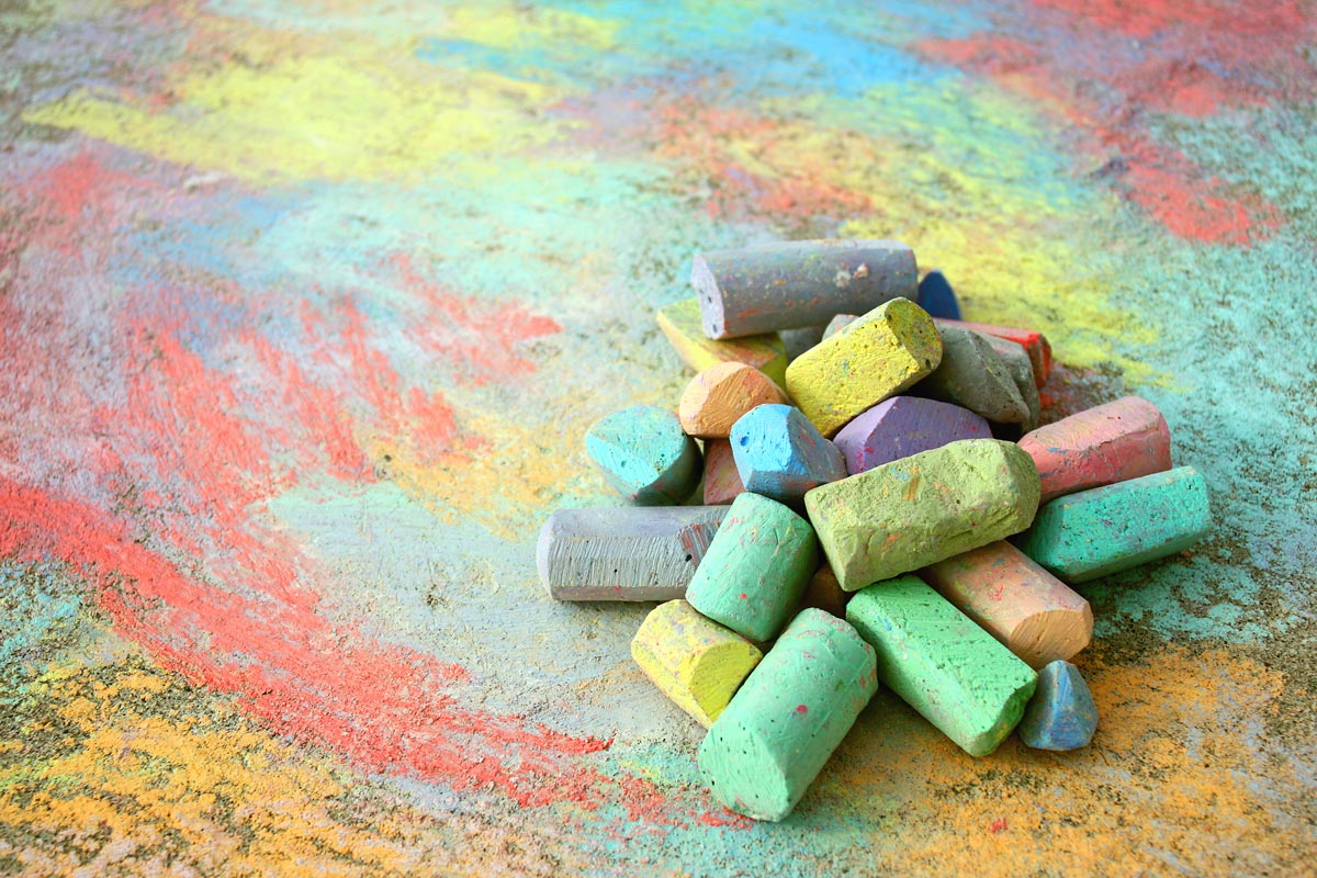 A pile of colorful chalk pieces on a surface covered in chalk scribbles