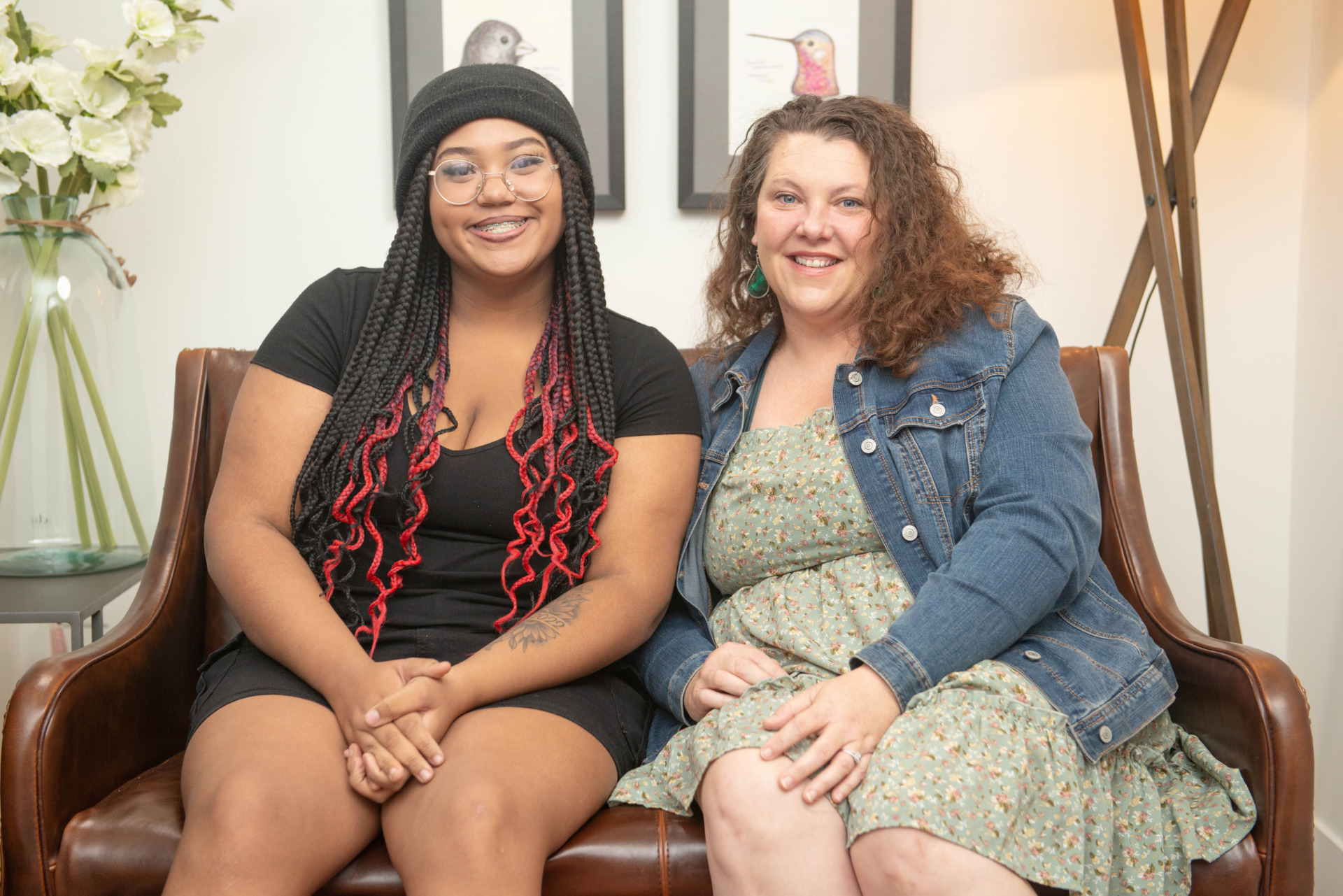 Adoptive mother and daughter of different races sit on a couch smiling