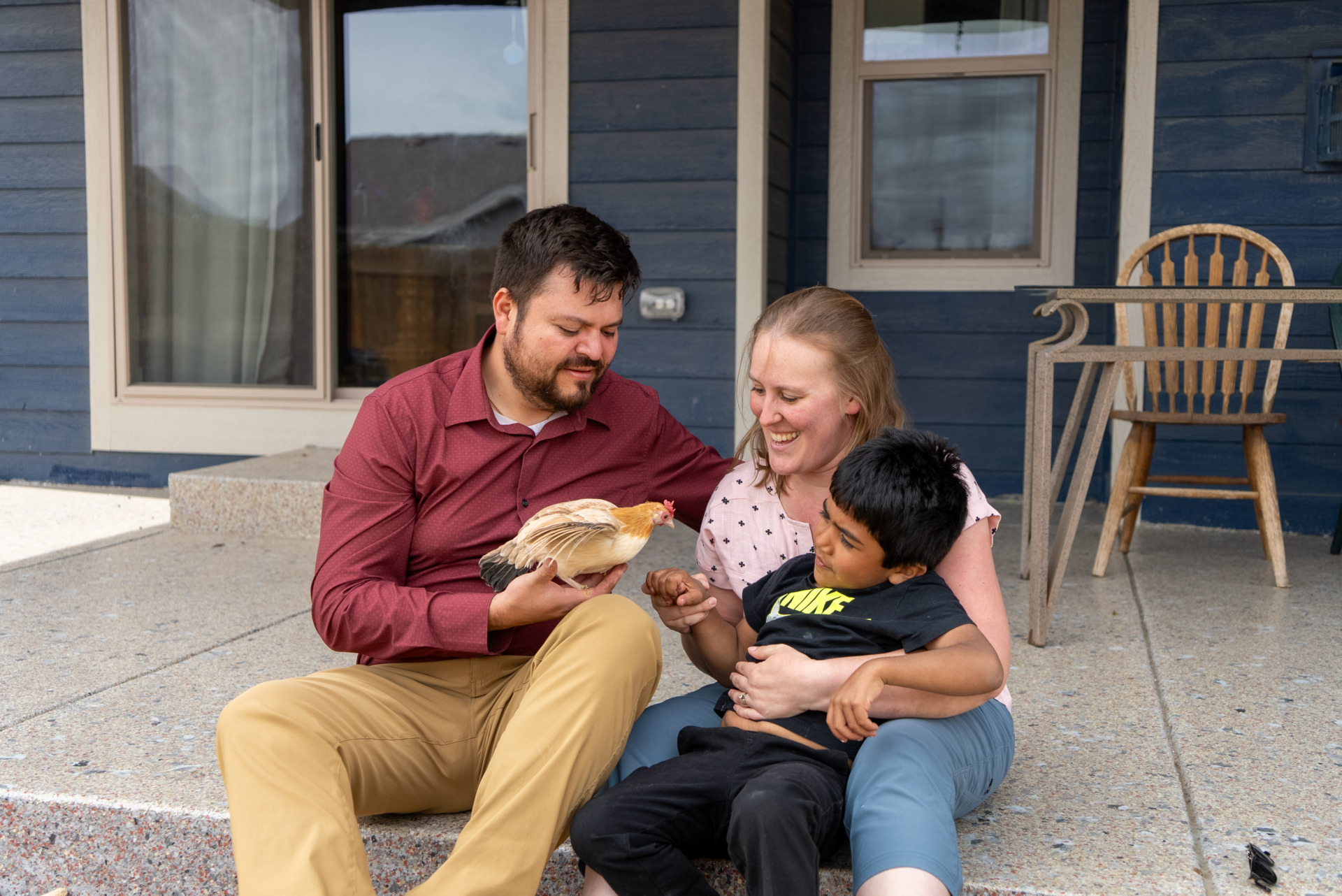 An adoptive dad and mom introduce their son to one of the chickens on their property.