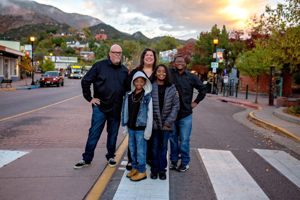 Multicultural family stands in a crosswalk with the sunset behind them.