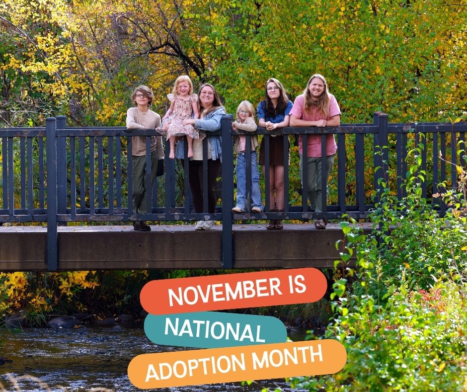 Family of six with four children and two parents stand on a bridge during fall. November is National Adoption Month is underneath in colorful lettering.