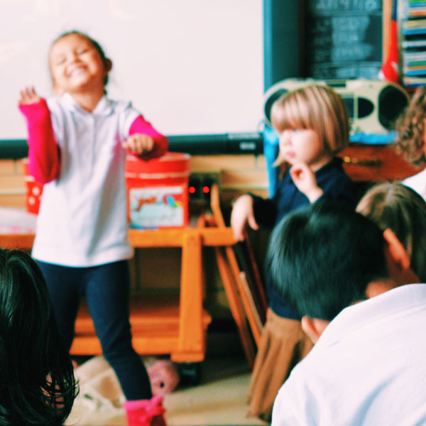 Varios niños bailan y juegan juntos en un salón de clases.