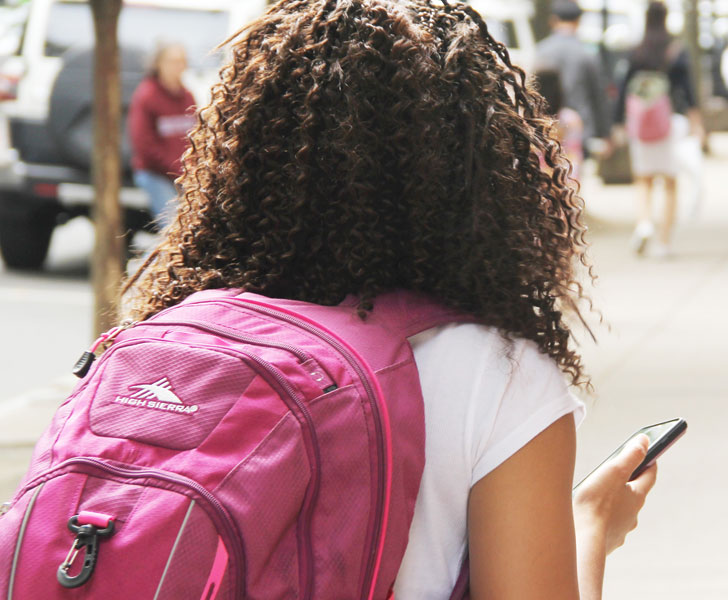 Chica caminando con mochila rosa.