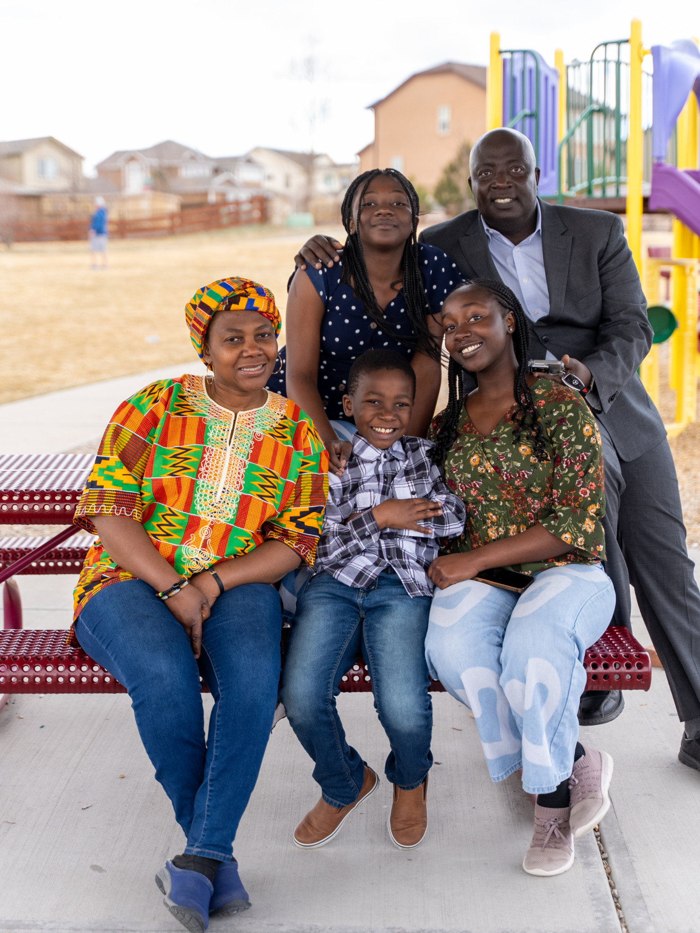 Una familia de crianza afroamericana de cinco personas juega en el parque infantil comunitario.