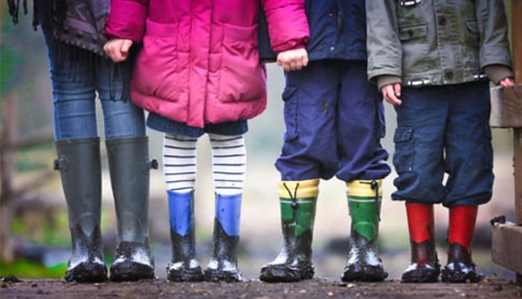 Cuatro niños con botas de lluvia