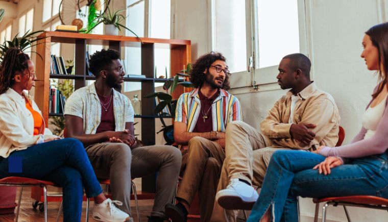 Diverse group of people sitting in a room talking.