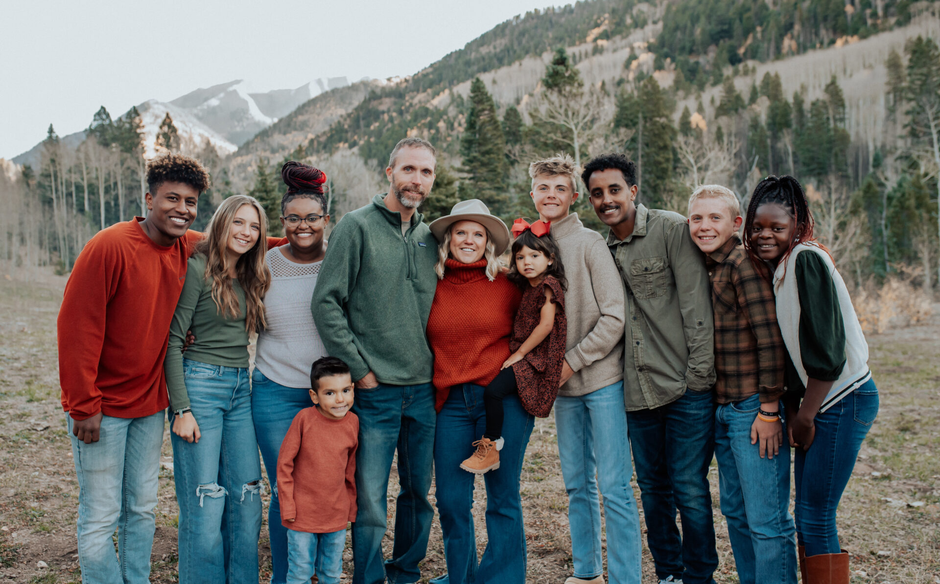 Family of eleven pose for a photo in the mountains Mom and dad, one adult six teens and two young children.