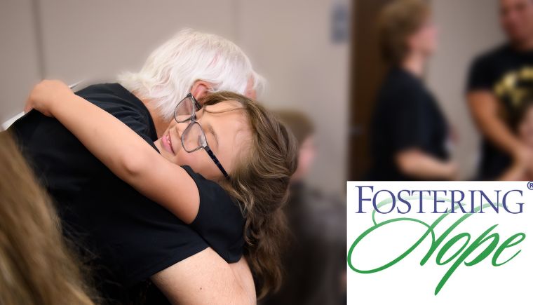 Older man hugging a young girl with the Fostering Hope logo in the corner.