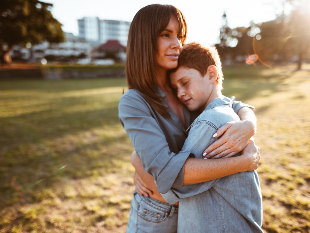 Mom and teenager hugging in a park