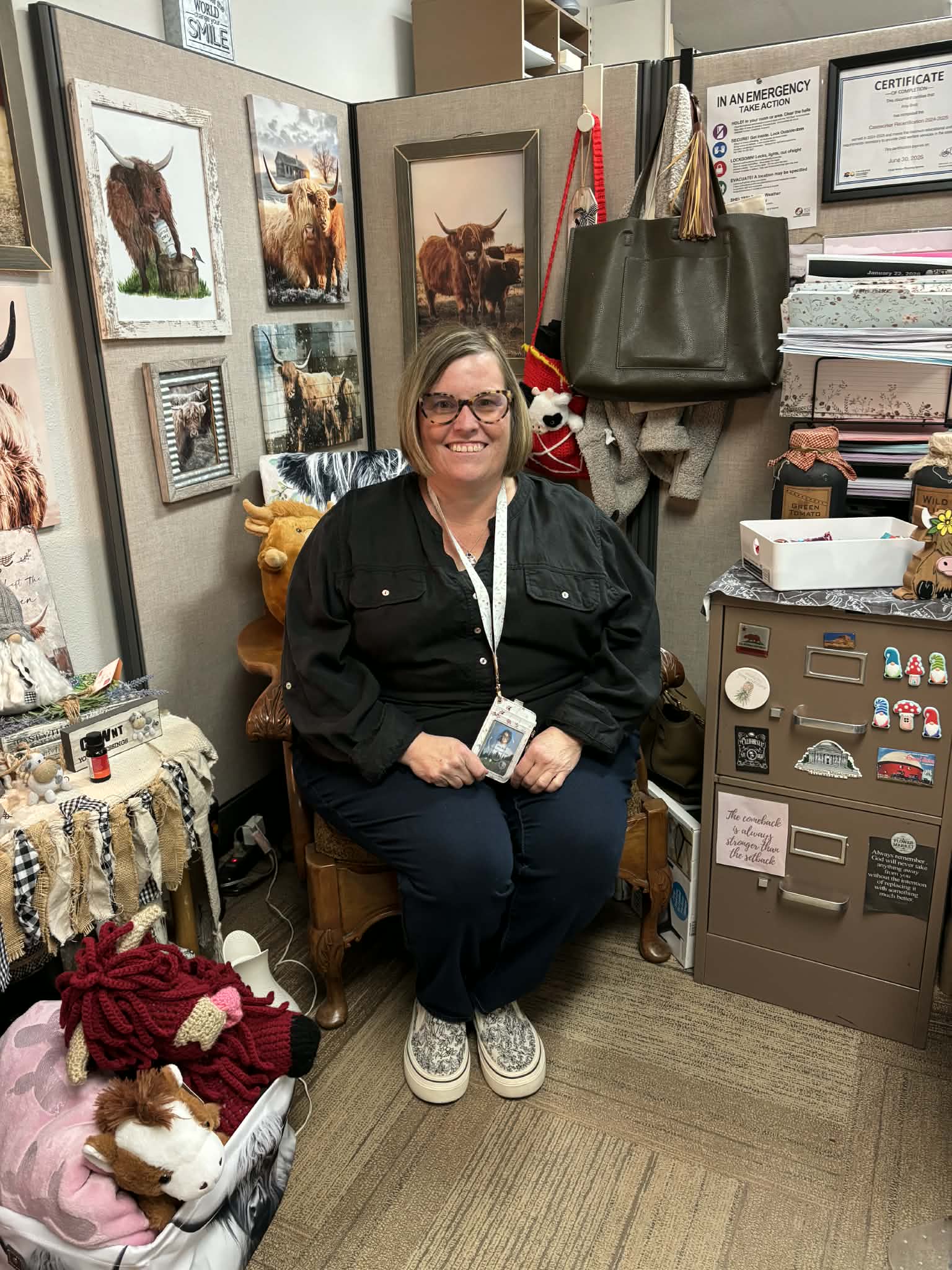 A woman wearing black with glasses sits in her office with pictures of buffalo on the walls.